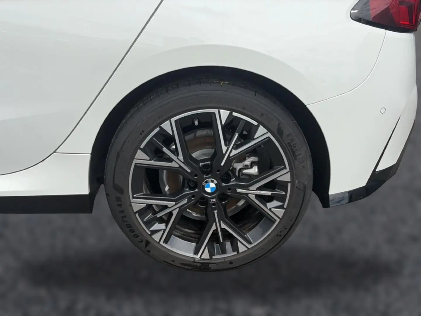 Gros plan sur la roue arrière droite avec jante alliage noire et argentée d’une BMW Série 1 blanche.