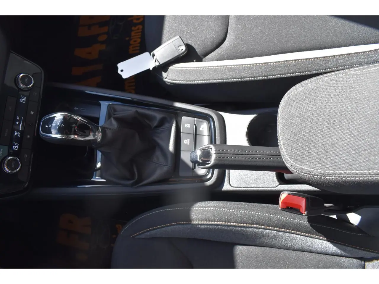 Vue plongeante sur la console centrale de la Skoda Scala gris graphite, avec levier de vitesse automatique et frein à main manuel.