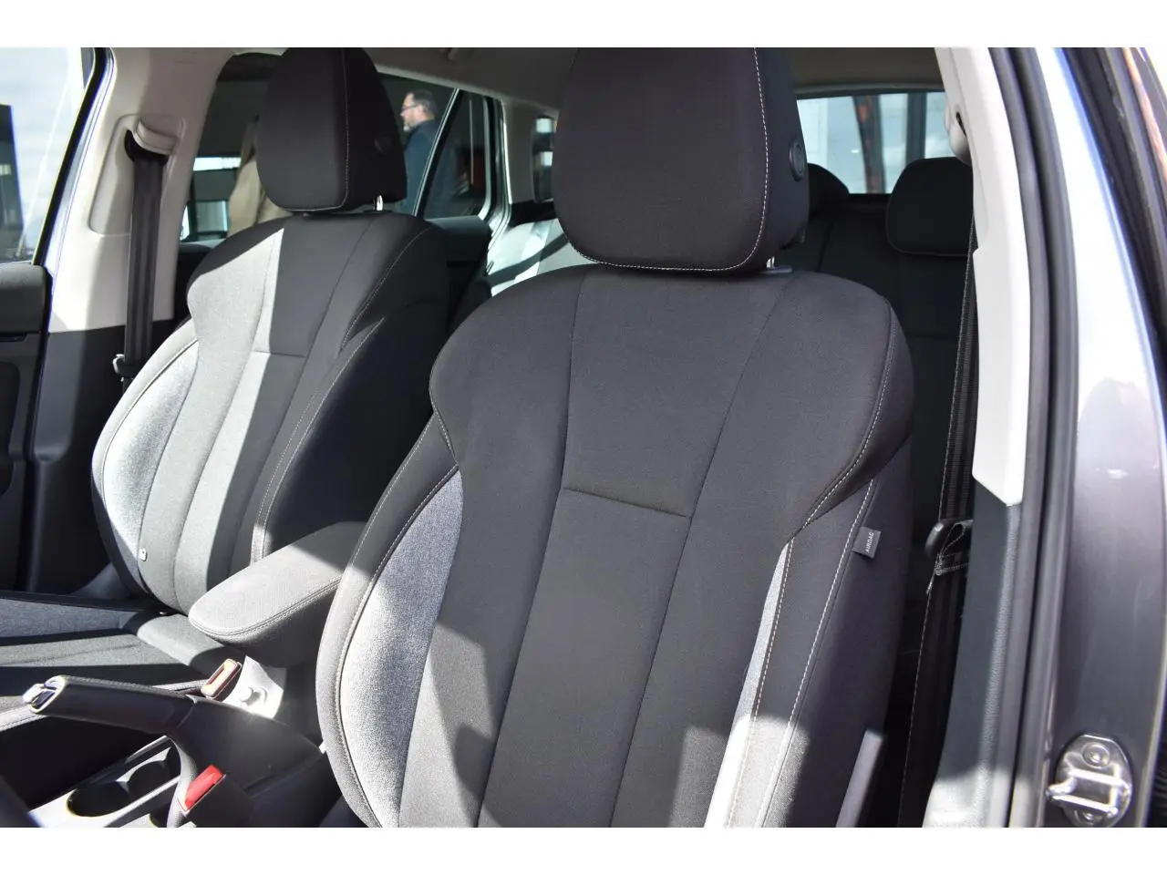 Vue rapprochée des sièges avant tissu gris et noir d’une Skoda Scala 2025, porte ouverte côté droit.
