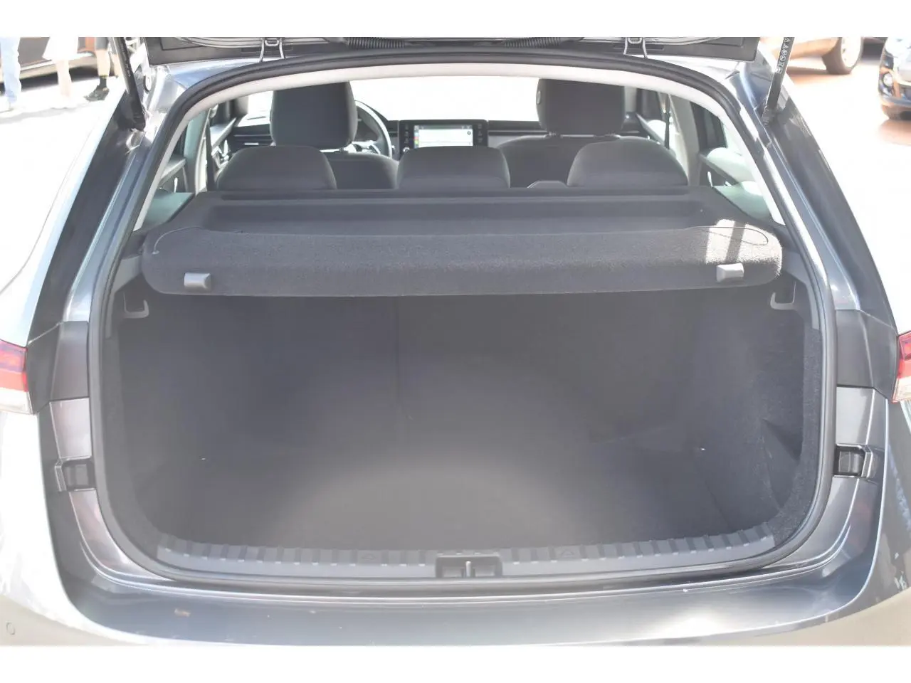 Coffre ouvert vu de l'arrière d'une Skoda Scala gris graphite, intérieur spacieux et banquette arrière visible.