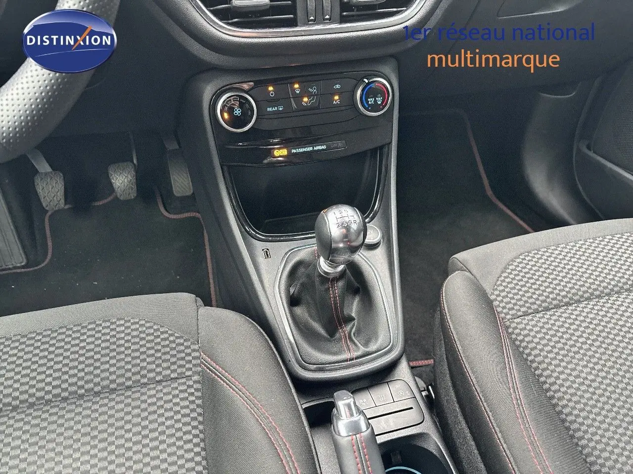 Intérieur du Ford Puma 2022 montrant la console centrale avec levier de vitesses manuel et sièges tissu noir à surpiqûres rouges.