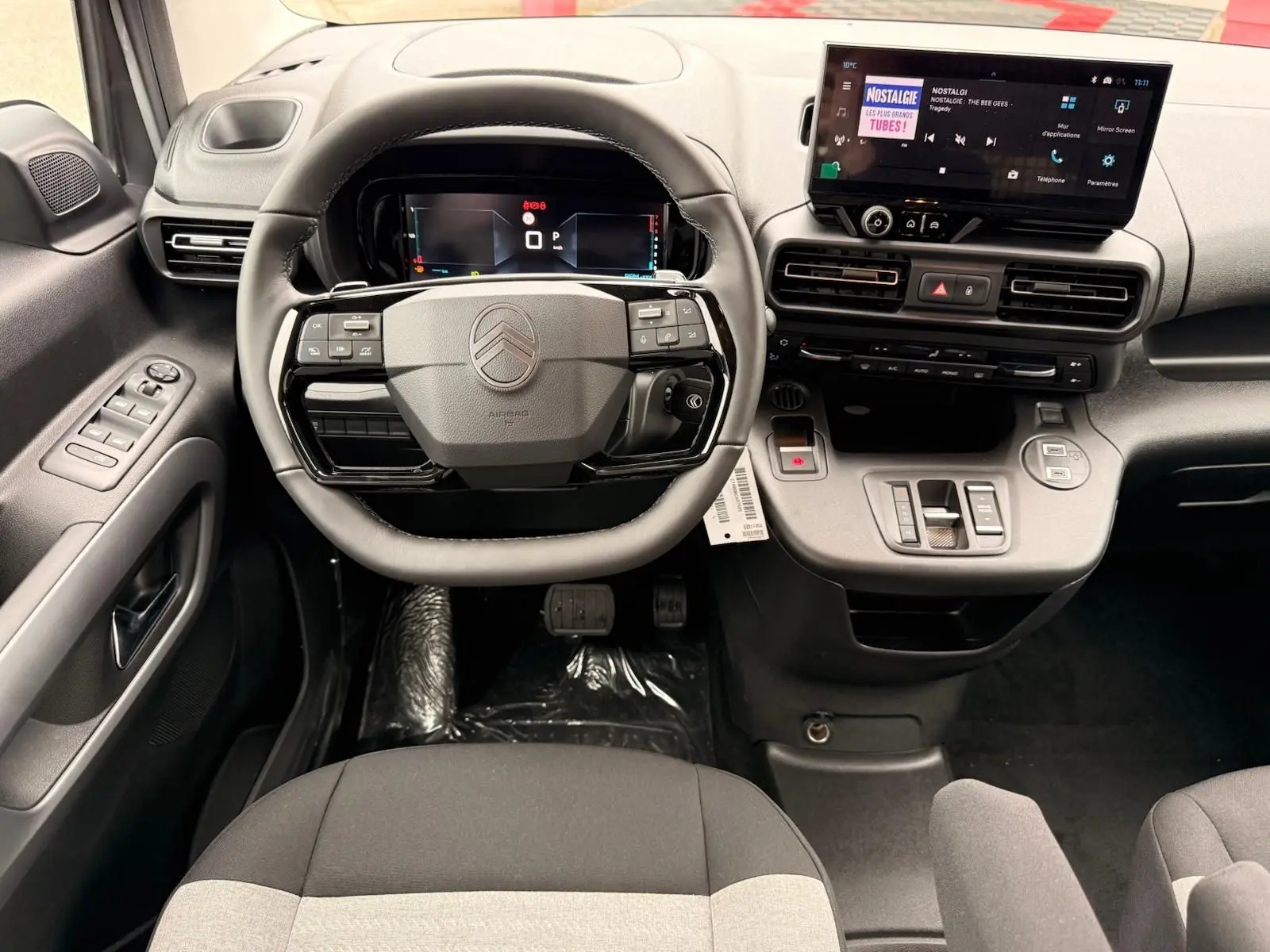 Vue intérieure avant du poste de conduite du Citroën Berlingo 2025, avec volant multifonction et écran tactile central.