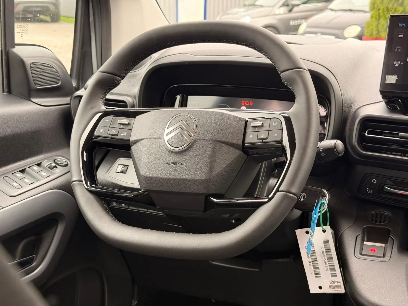 Vue rapprochée du volant cuir noir de la Citroën Berlingo 2025 avec commandes intégrées et tableau de bord numérique.
