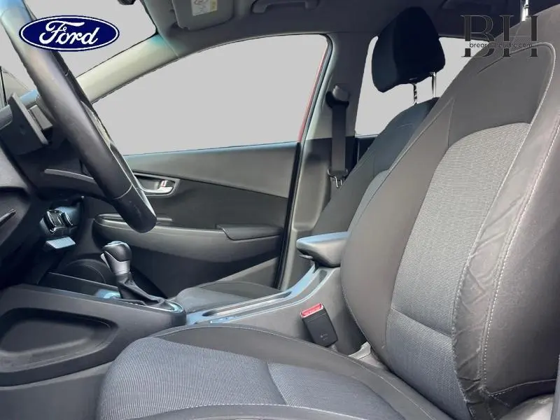 Vue intérieure côté conducteur du Hyundai Kona 1.6 GDi Hybrid 2022 avec sièges tissu noir et accoudoir central.