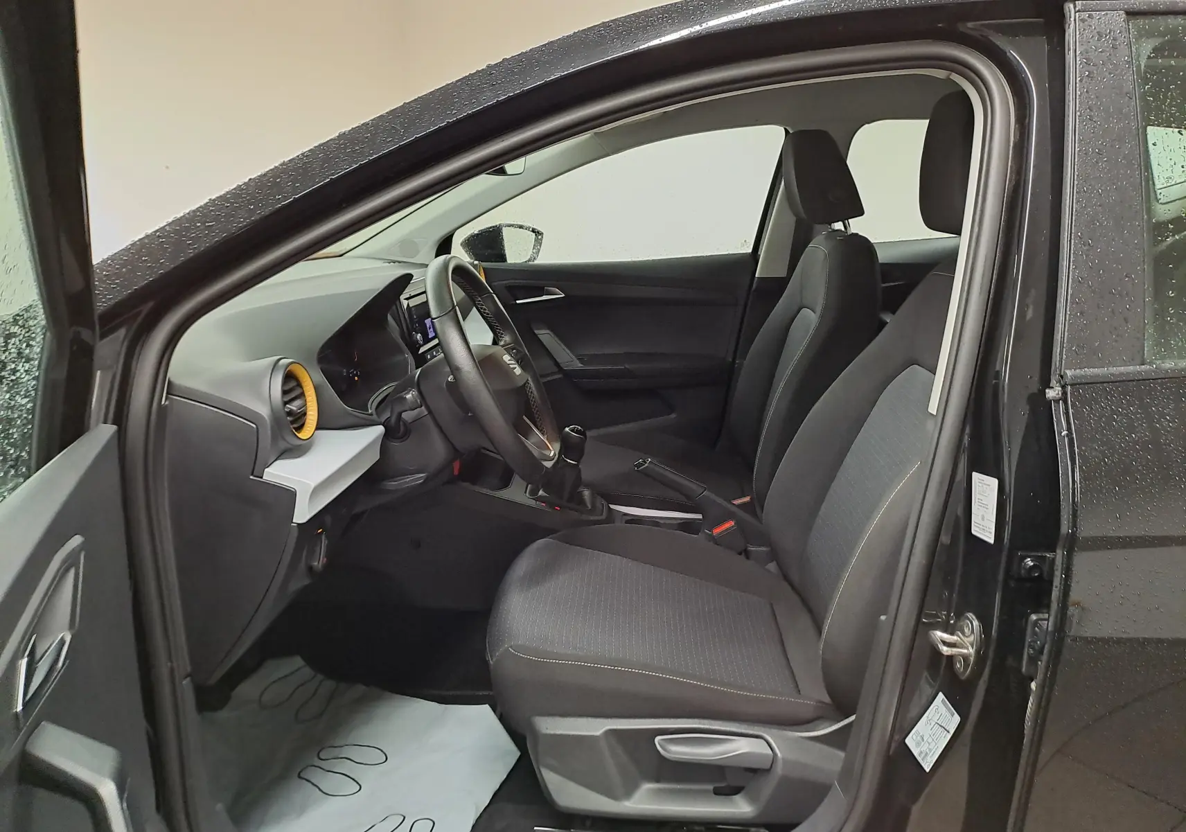 Vue intérieure côté conducteur de la SEAT Ibiza noire Minuit 2024, montrant les sièges et le tableau de bord moderne.