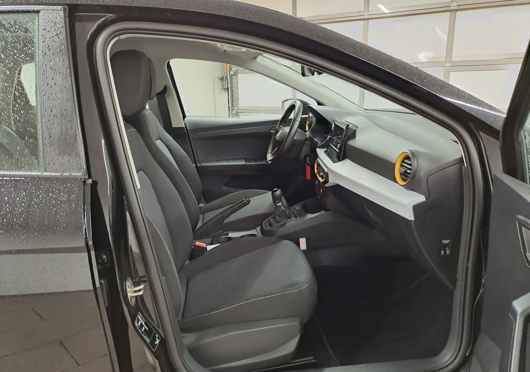 Vue intérieure côté conducteur de la SEAT Ibiza noir minuit 2024, avec tableau de bord moderne et sièges tissu gris.