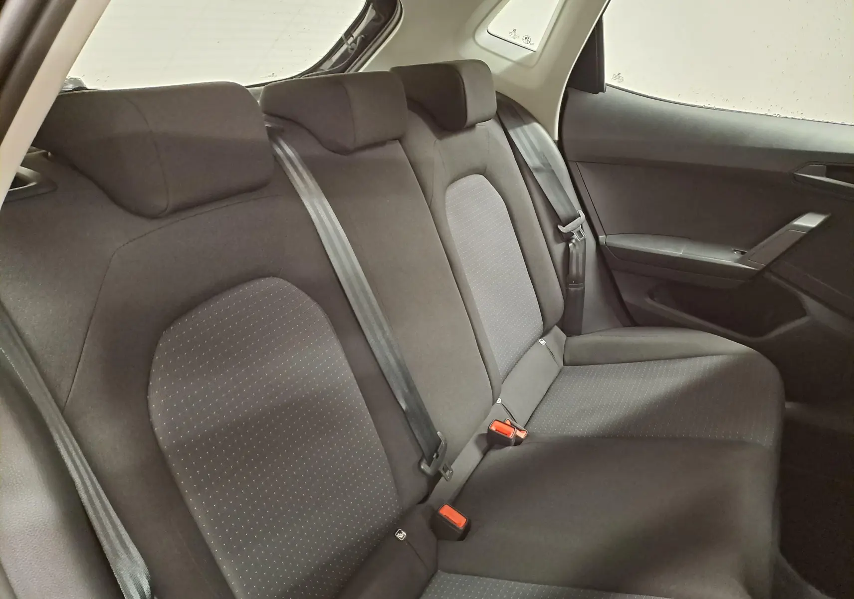 Vue intérieure du siège arrière droit de la SEAT Ibiza 2024, tissu noir avec ceintures de sécurité visibles.