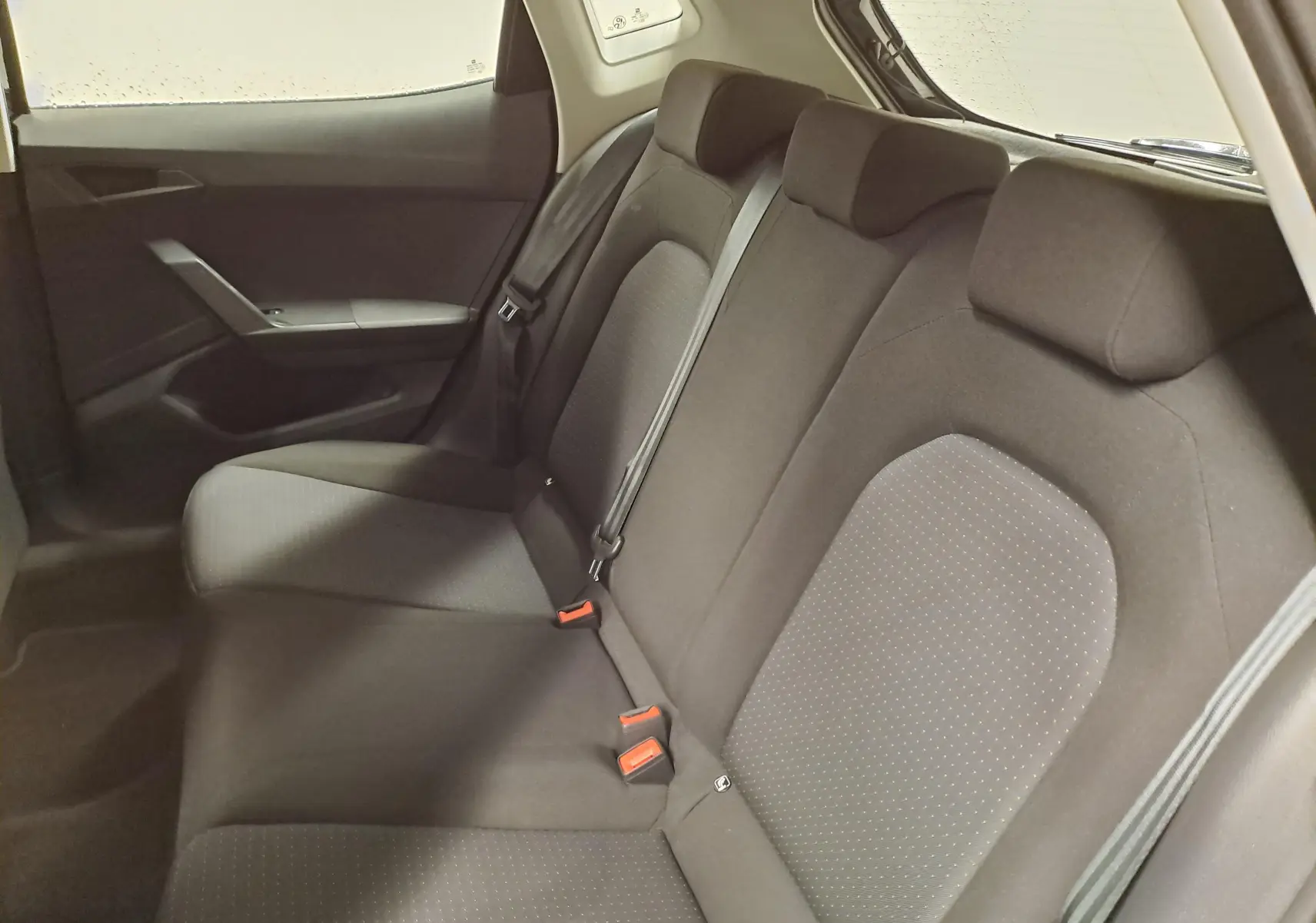 Vue intérieure côté droit des sièges arrière noirs de la SEAT Ibiza 2024 avec ceintures et appuie-têtes visibles.
