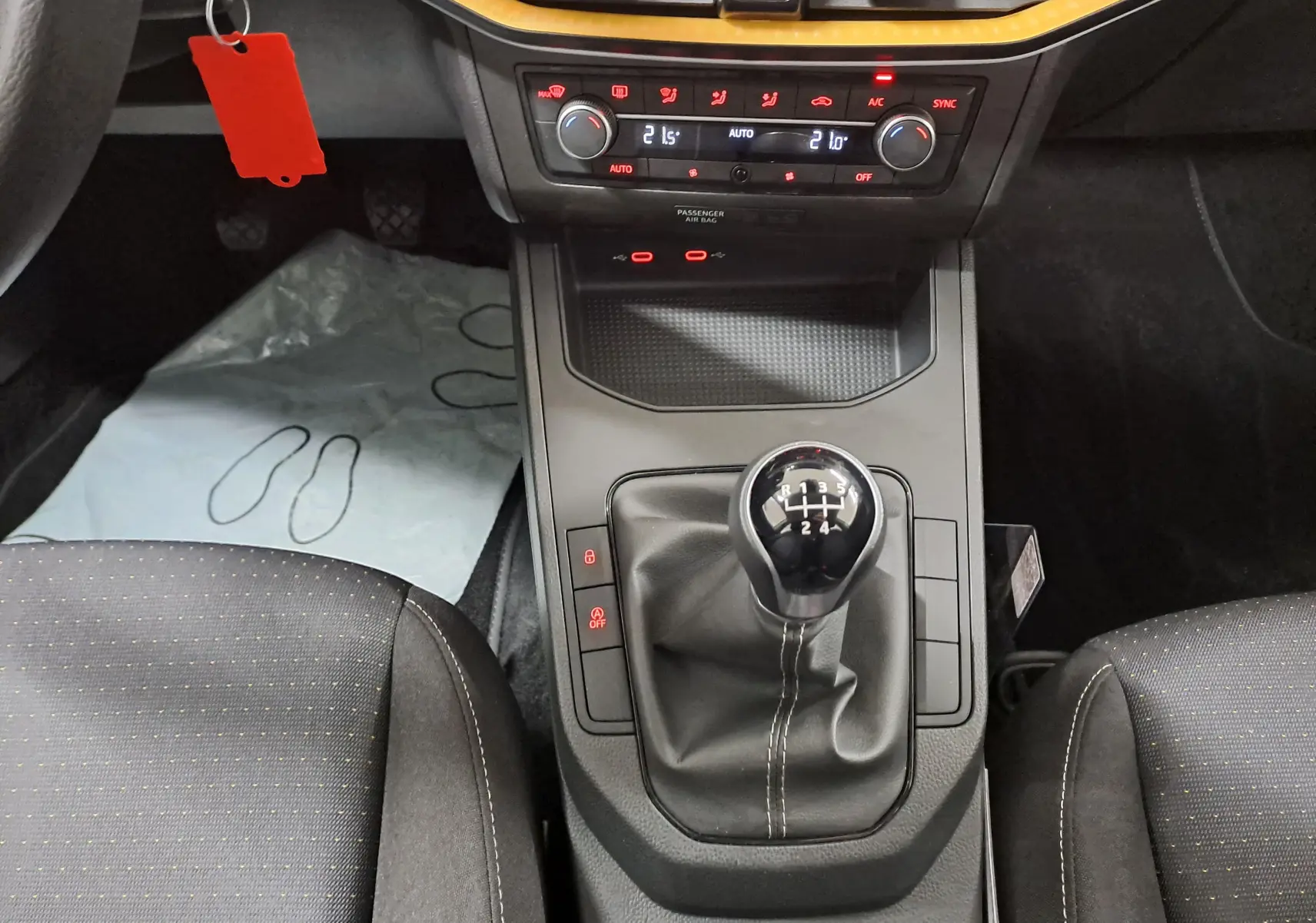 Vue intérieure centrée sur la console centrale de la SEAT Ibiza 2024, mettant en valeur le levier de vitesses manuel et la climatisation bi-zone.
