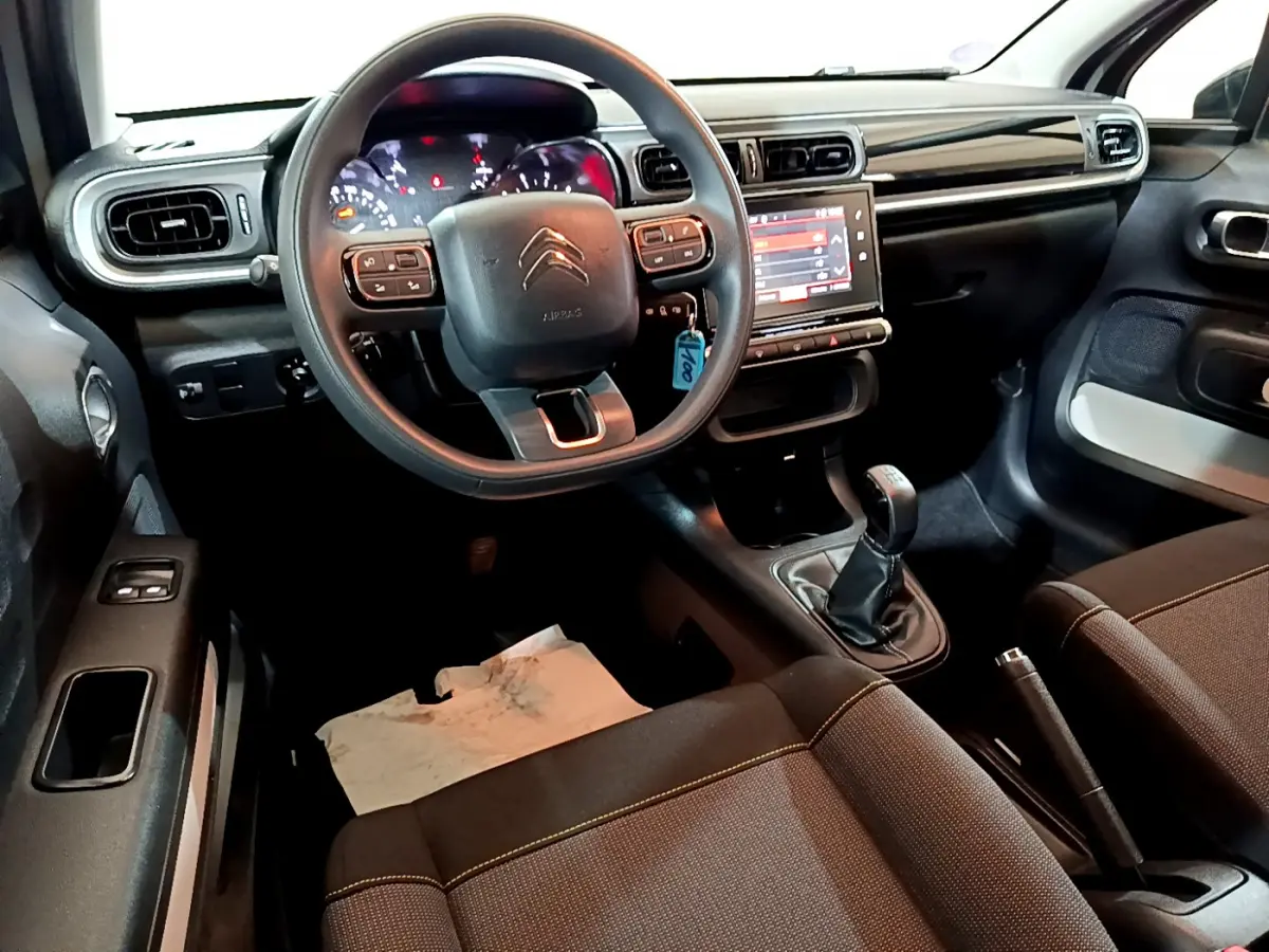 Vue intérieure avant de la Citroën C3 beige 2022, volant multifonctions, écran tactile et boîte manuelle visible.