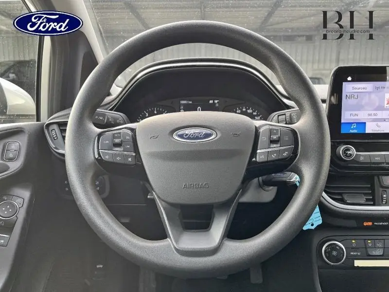Vue intérieure centrée sur le volant noir de la Ford Fiesta 2020 avec tableau de bord et écran tactile visible.