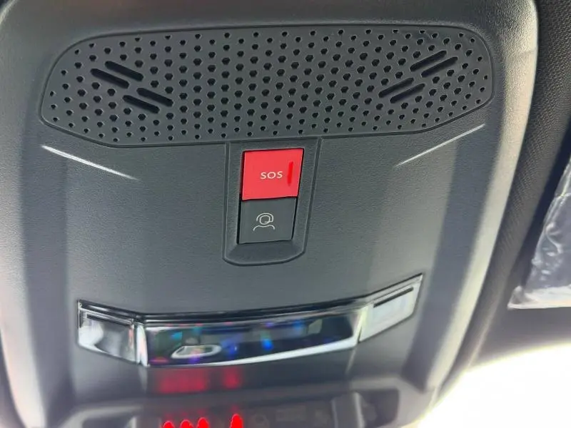 Vue en gros plan du plafonnier intérieur noir avec bouton SOS rouge du Peugeot 2008 bleu hybride 2025.