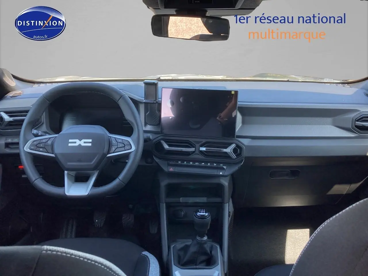 Vue intérieure avant du tableau de bord et volant du Dacia Duster 2026 avec écran tactile et boîte manuelle.