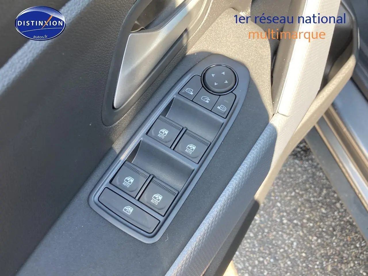 Gros plan sur les commandes des vitres électriques côté conducteur du Dacia Duster gris schiste 2026.