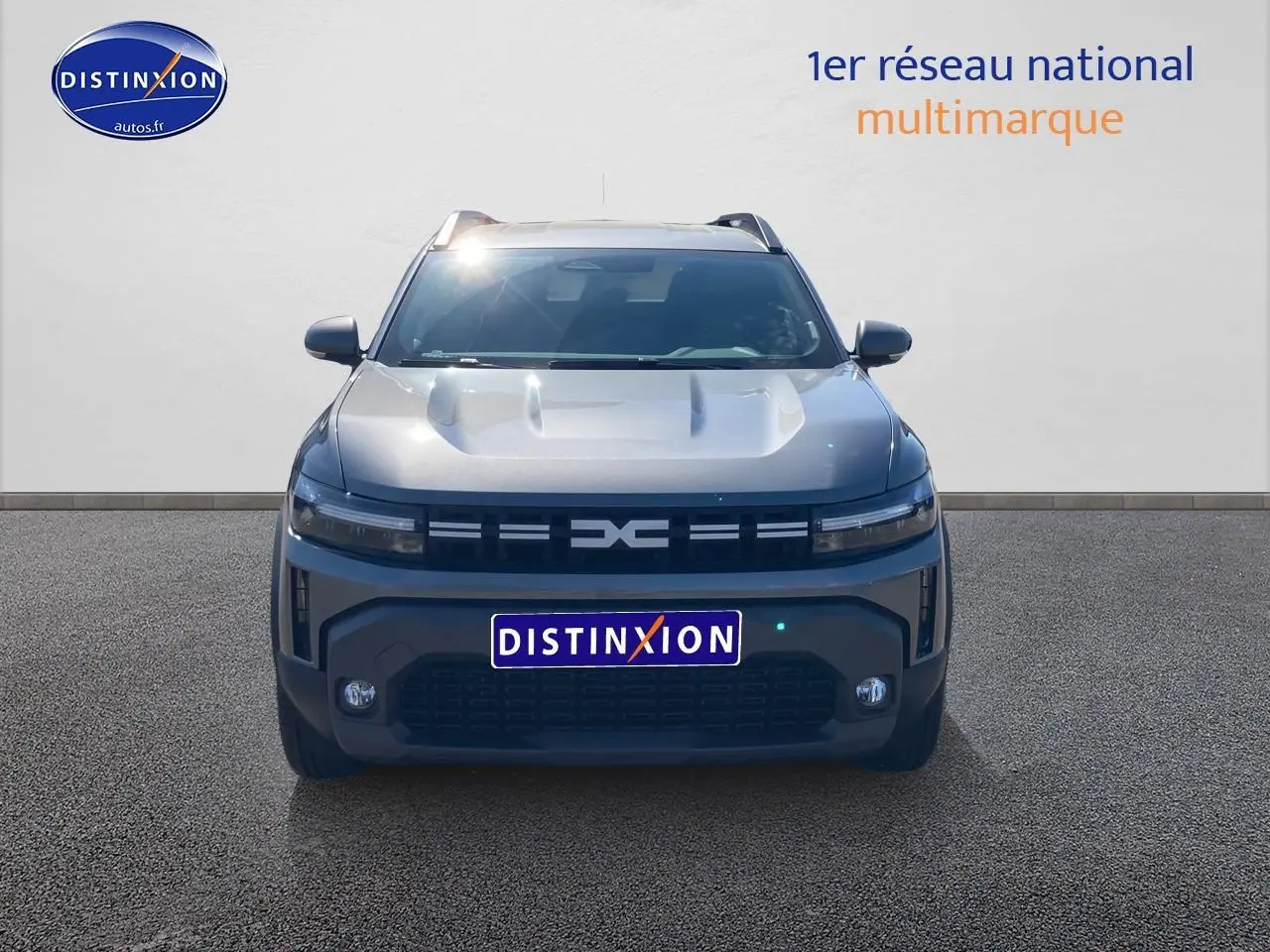 Vue frontale d'un Dacia Duster 2026 gris schiste avec calandre noire et phares LED fins allumés.