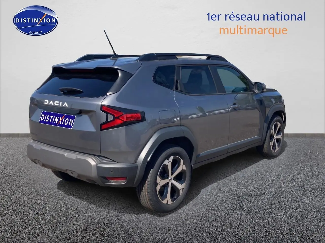 Vue 3/4 arrière droite du Dacia Duster gris schiste avec barres de toit et jantes alu distinctives.