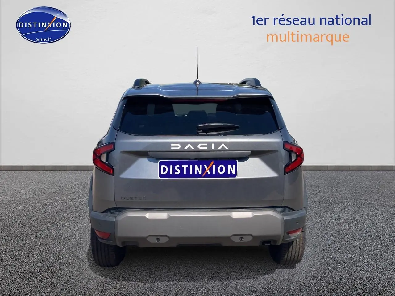 Vue arrière du Dacia Duster gris schiste 2026 avec feux LED et barres de toit visibles.