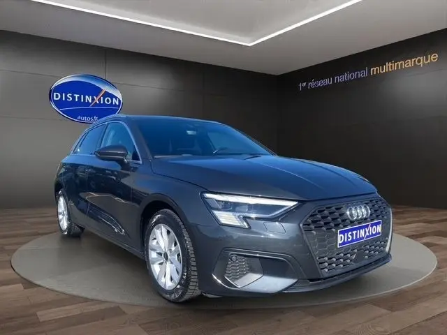 Audi A3 30 TDI Business Line gris foncé vue 3/4 avant droit avec calandre hexagonale et phares LED allumés.