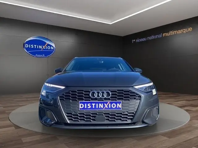 Vue frontale d'une Audi A3 30 TDI 116 Business Line gris foncé avec calandre hexagonale et feux LED allumés.
