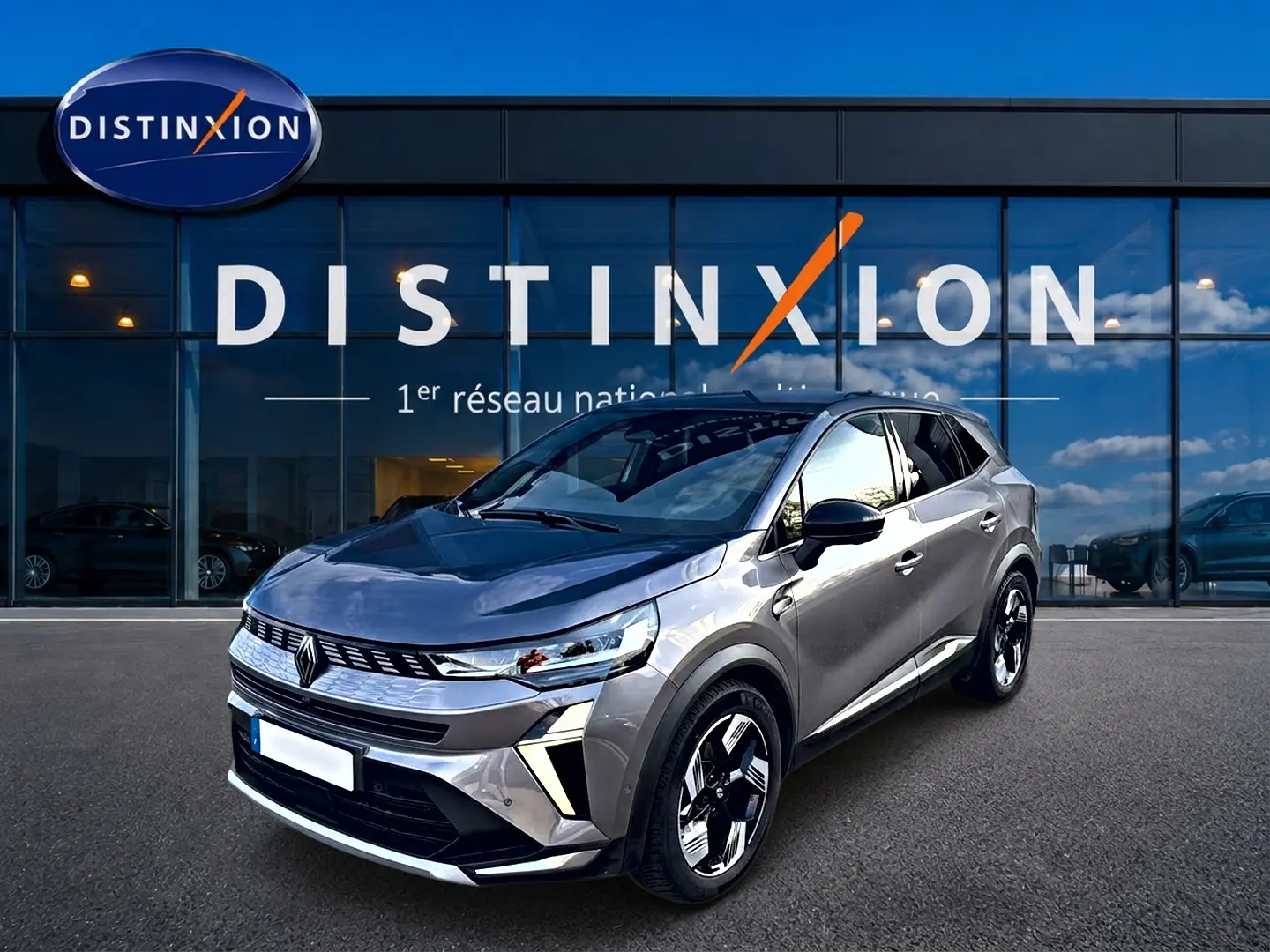 Renault Symbioz gris cassiopée en 3/4 avant droit, avec calandre moderne et jantes bicolores distinctives.