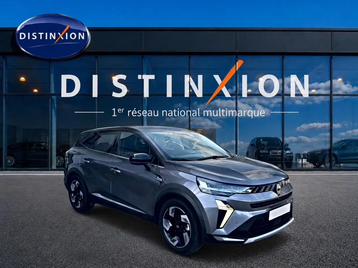Renault Symbioz gris cassiopée en 3/4 avant droit, avec phares LED et jantes modernes devant vitrine Distinxion.