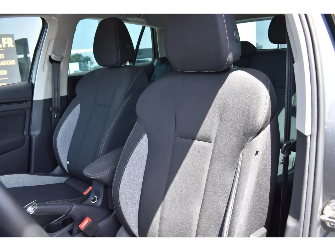 Vue intérieure rapprochée des sièges avant en tissu noir et gris clair du Skoda Scala 2025, côté conducteur ouvert.