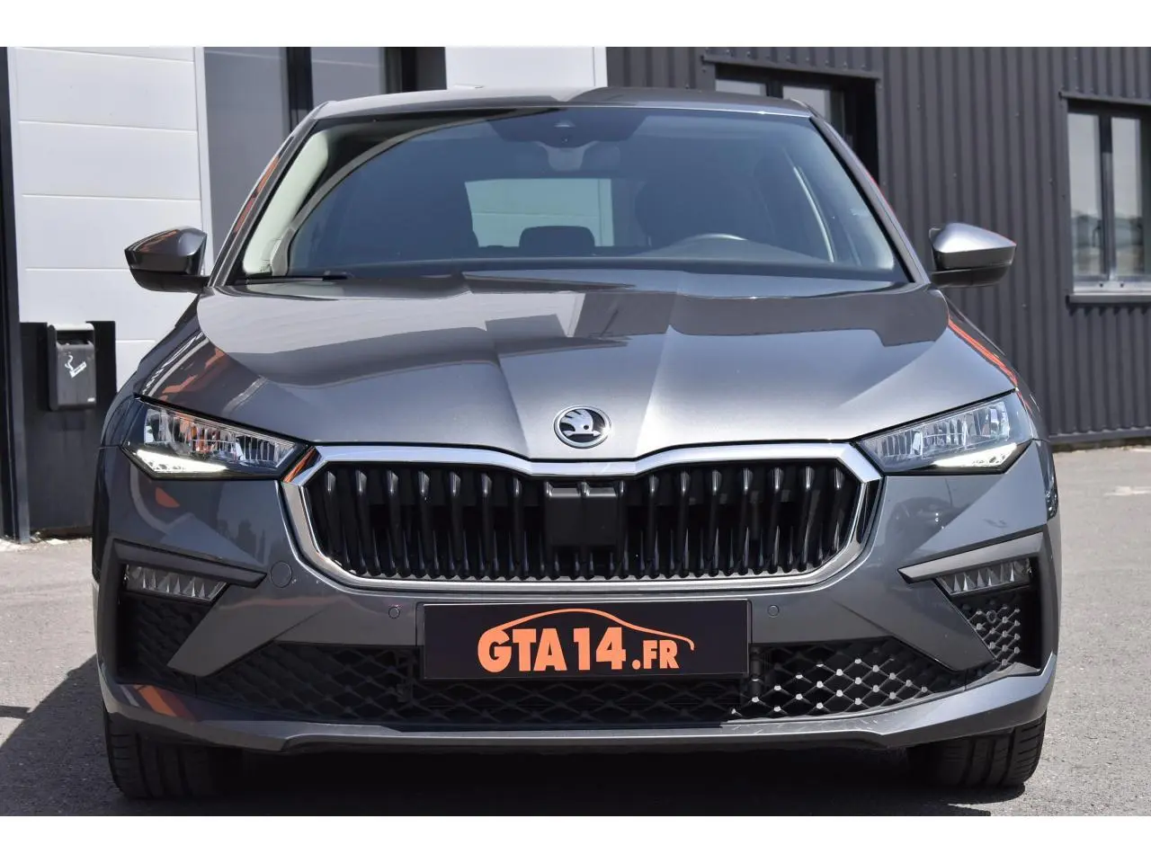 Vue avant d'une Skoda Scala 2025 en gris graphite métallique avec calandre noire et phares LED allumés.