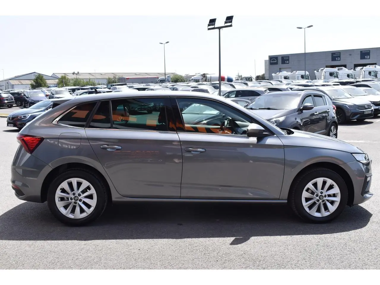 Vue latérale droite d'une Skoda Scala 2025 gris graphite métallisé avec jantes alliage 16 pouces sur parking.