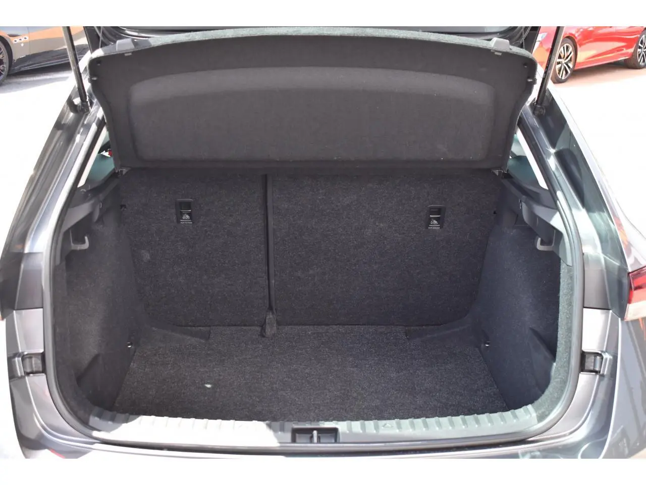 Coffre ouvert vu de l'arrière d'une Skoda Scala 2025 Graphite Grey Metallic, intérieur spacieux et tapis gris foncé.