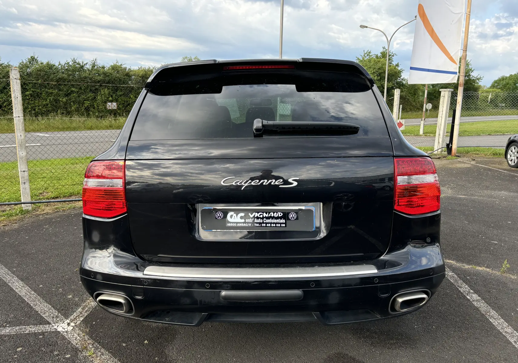 Vue arrière d'un Porsche Cayenne S noir de 2007 avec double sortie d'échappement et feux arrière rouges.