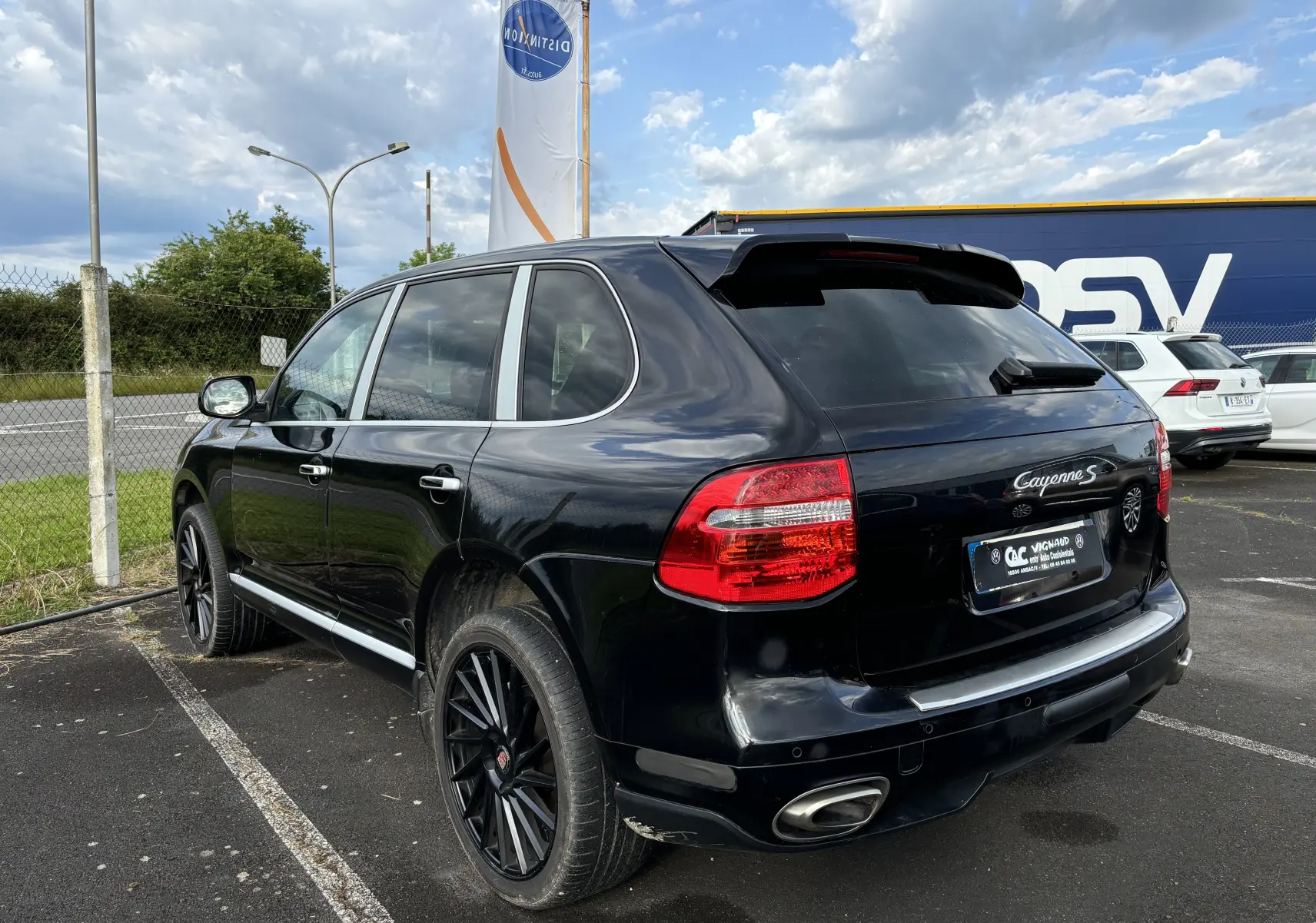 Vue 3/4 arrière droite d'un Porsche Cayenne S noir de 2007 avec jantes noires et feux arrière rouges.
