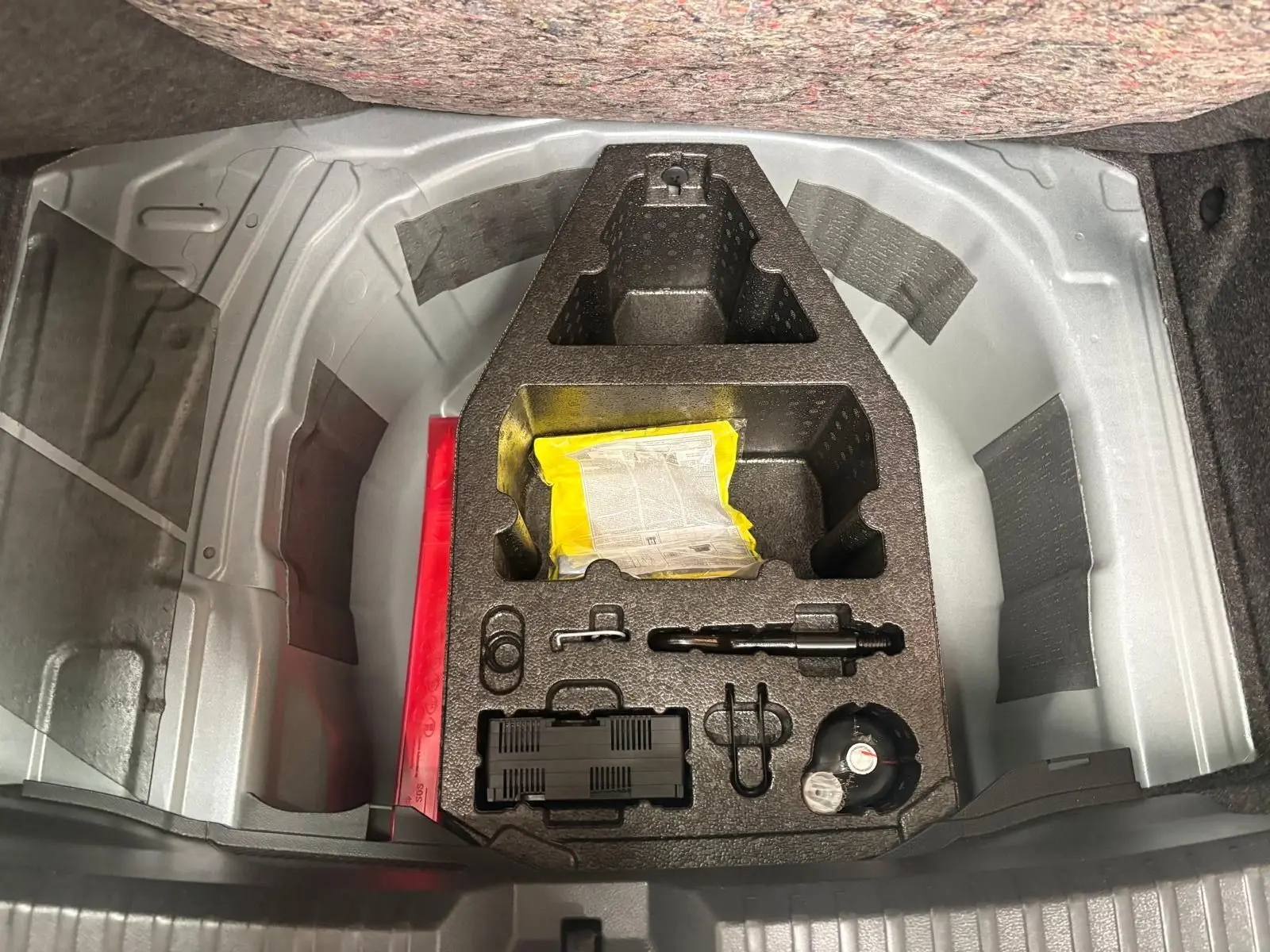 Coffre ouvert montrant le rangement d’outils et accessoires sous le plancher d’une SEAT Ibiza gris magnétique 2024.