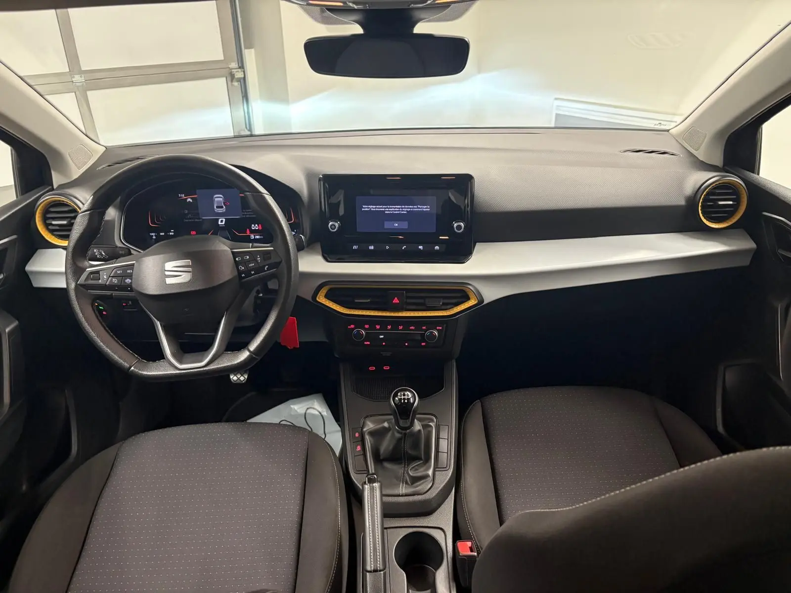 Intérieur de la SEAT Ibiza 2024 gris magnétique, vue frontale du tableau de bord avec volant et console centrale manuelle.