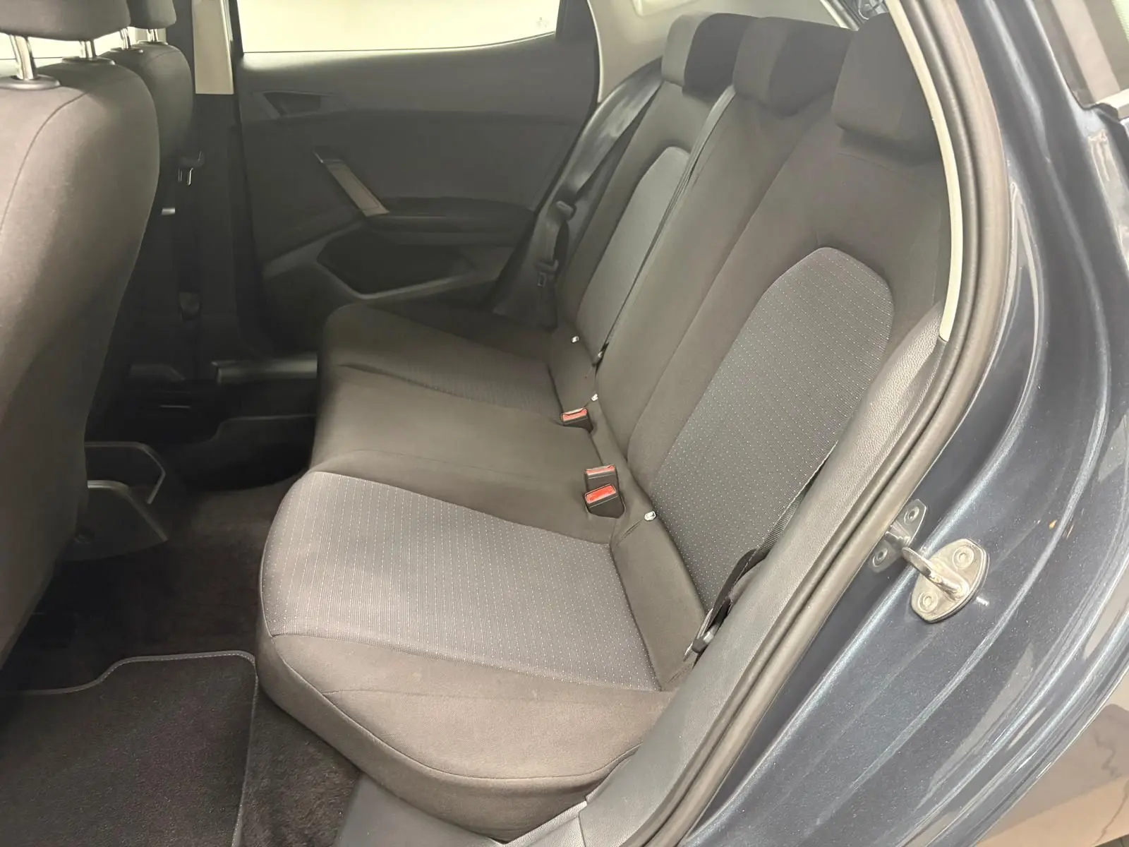 Vue intérieure côté droit sur les sièges arrière en tissu gris d’une SEAT Ibiza 2024 gris magnétique, porte ouverte.