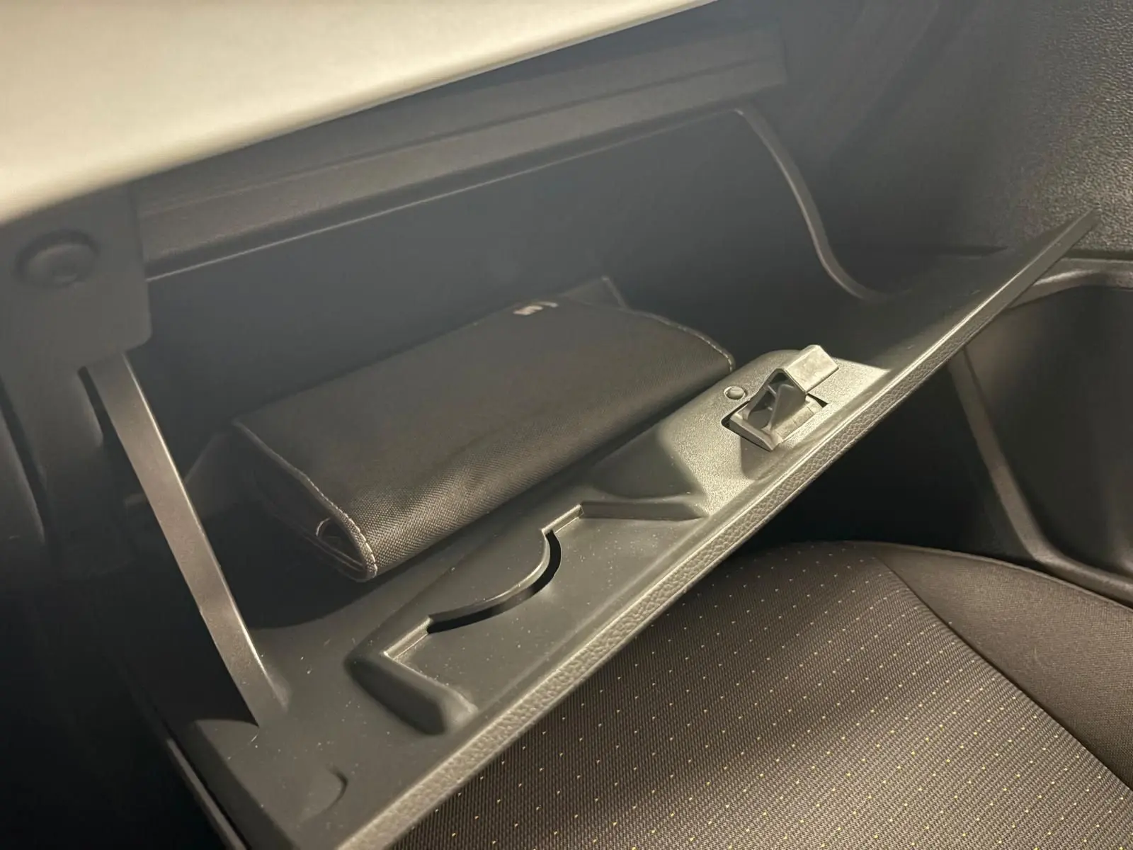 Vue rapprochée de la boîte à gants ouverte du SEAT Ibiza gris magnétique, avec un étui noir à l'intérieur.