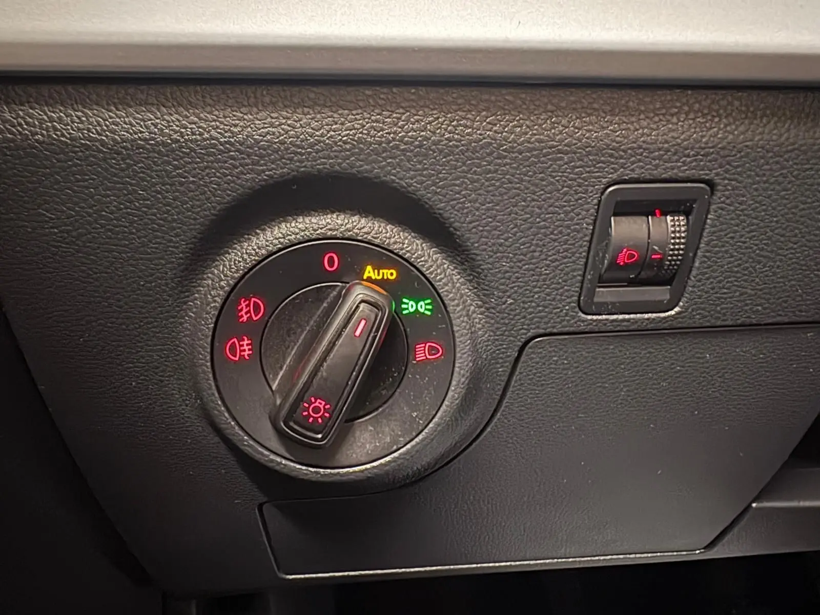 Détail du sélecteur de phares avec réglage automatique sur le tableau de bord noir d'une SEAT Ibiza 2024.