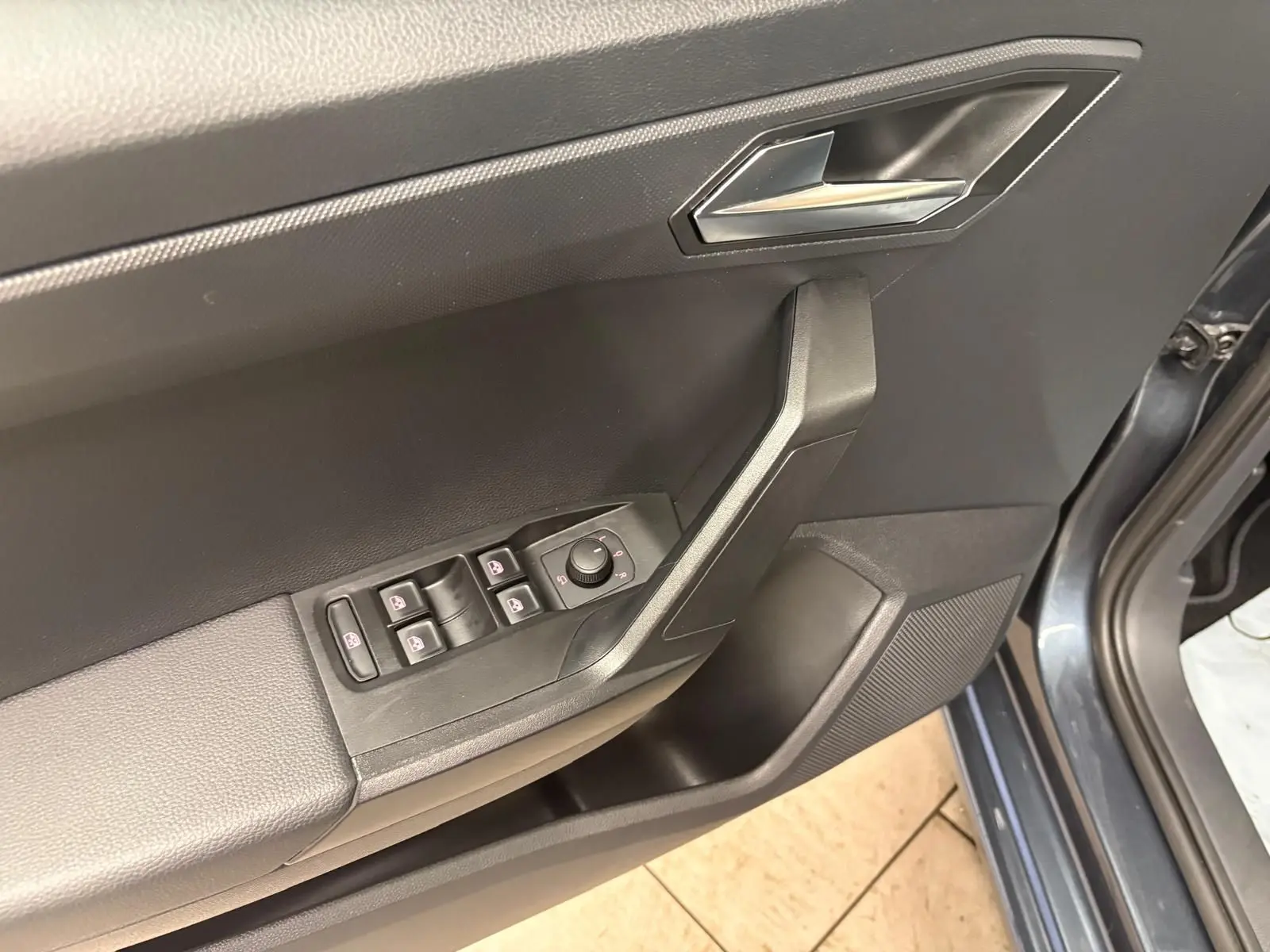 Intérieur côté conducteur de la SEAT Ibiza 2024 gris magnétique, avec commandes des vitres et rétroviseurs sur la portière ouverte.