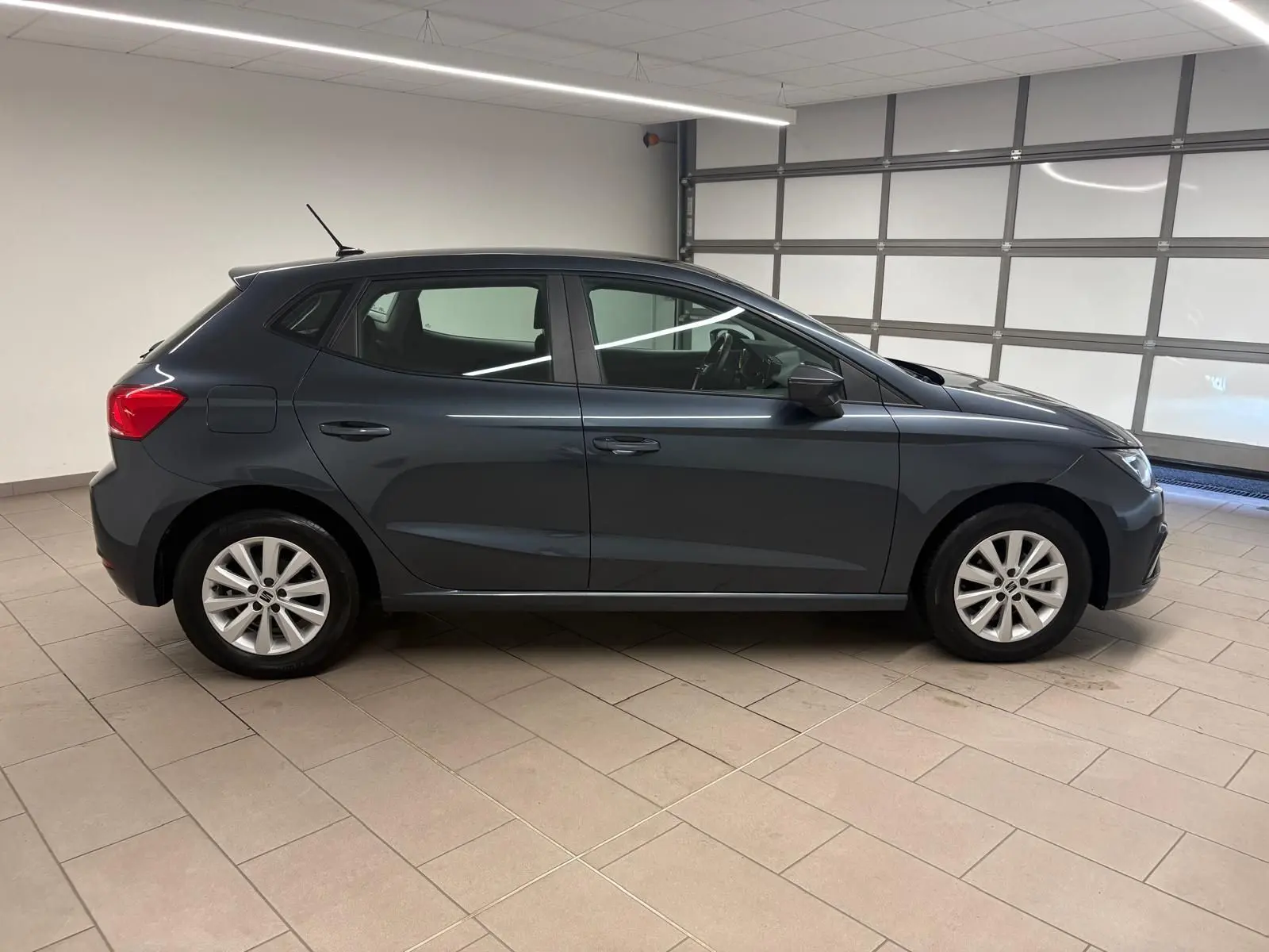 SEAT Ibiza 2024 gris magnétique vue de profil côté gauche dans un garage, jantes alliage et lignes épurées.