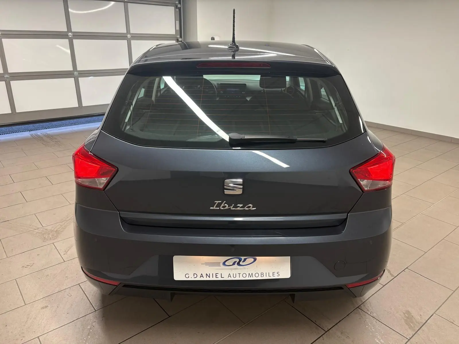 Vue arrière d'une SEAT Ibiza 2024 gris magnétique, avec feux rouges anguleux et logo distinctif sur hayon.