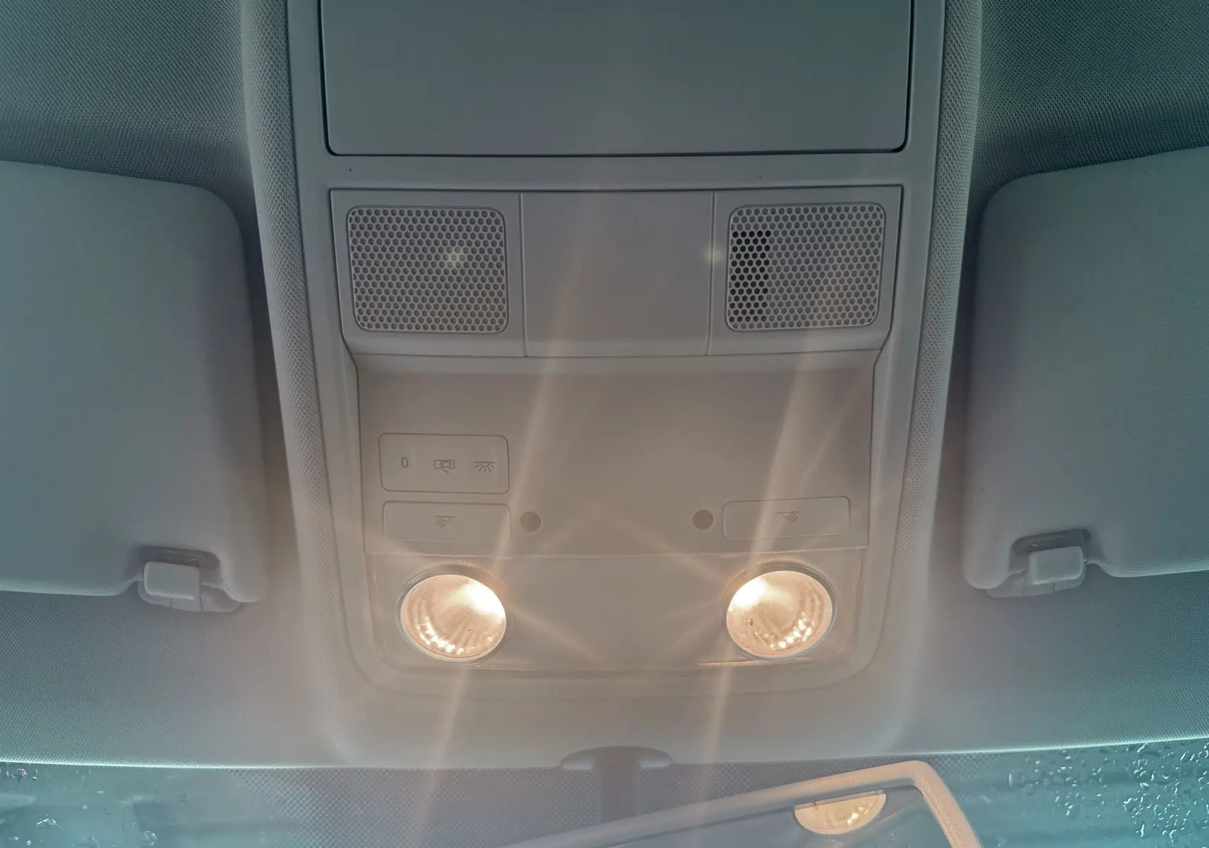 Plafonnier intérieur allumé vu de dessous dans un Volkswagen Tiguan blanc, avec pare-soleil et rétroviseur partiellement visible.