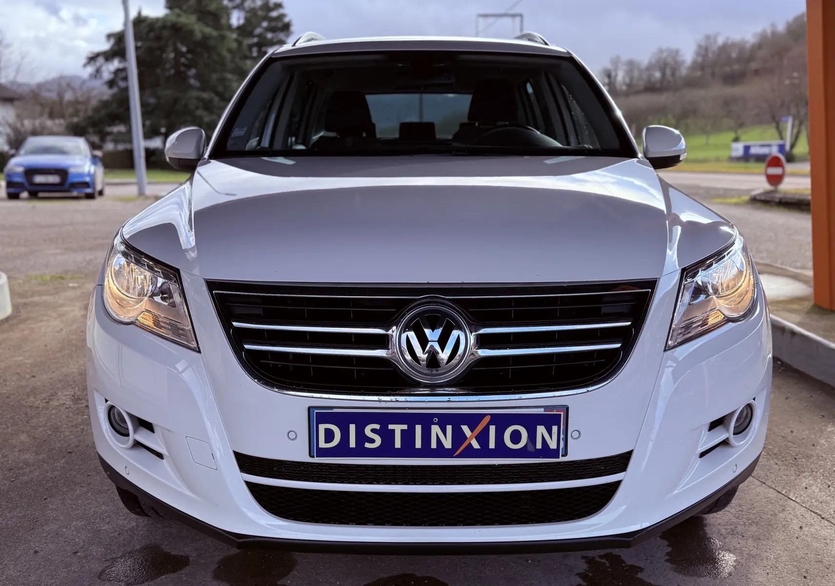 Vue frontale d'un Volkswagen Tiguan blanc de 2010 avec calandre noire et plaque Distinxion visible.