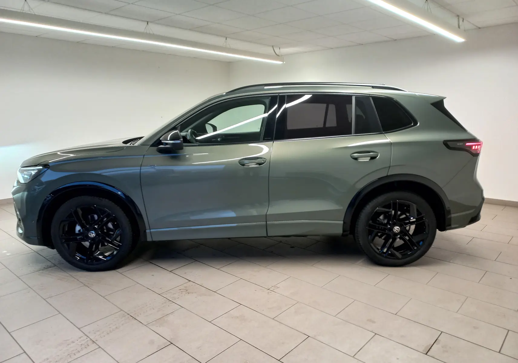 Volkswagen Tiguan 2025 vert Cipressino vu de profil côté gauche avec jantes noires et vitres surteintées.