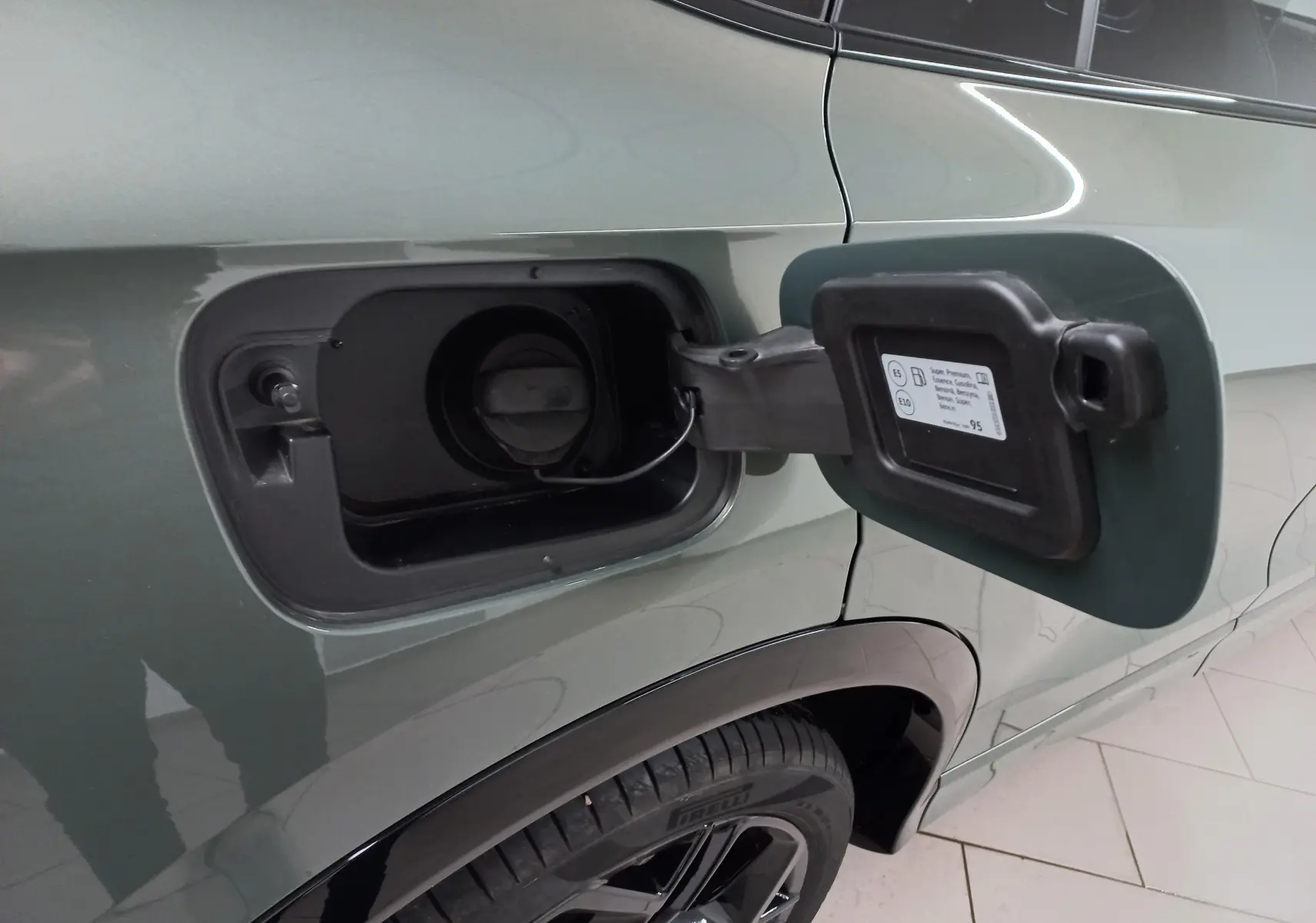 Gros plan sur la trappe à carburant ouverte côté gauche d’un Volkswagen Tiguan Vert Cipressino avec jante noire.