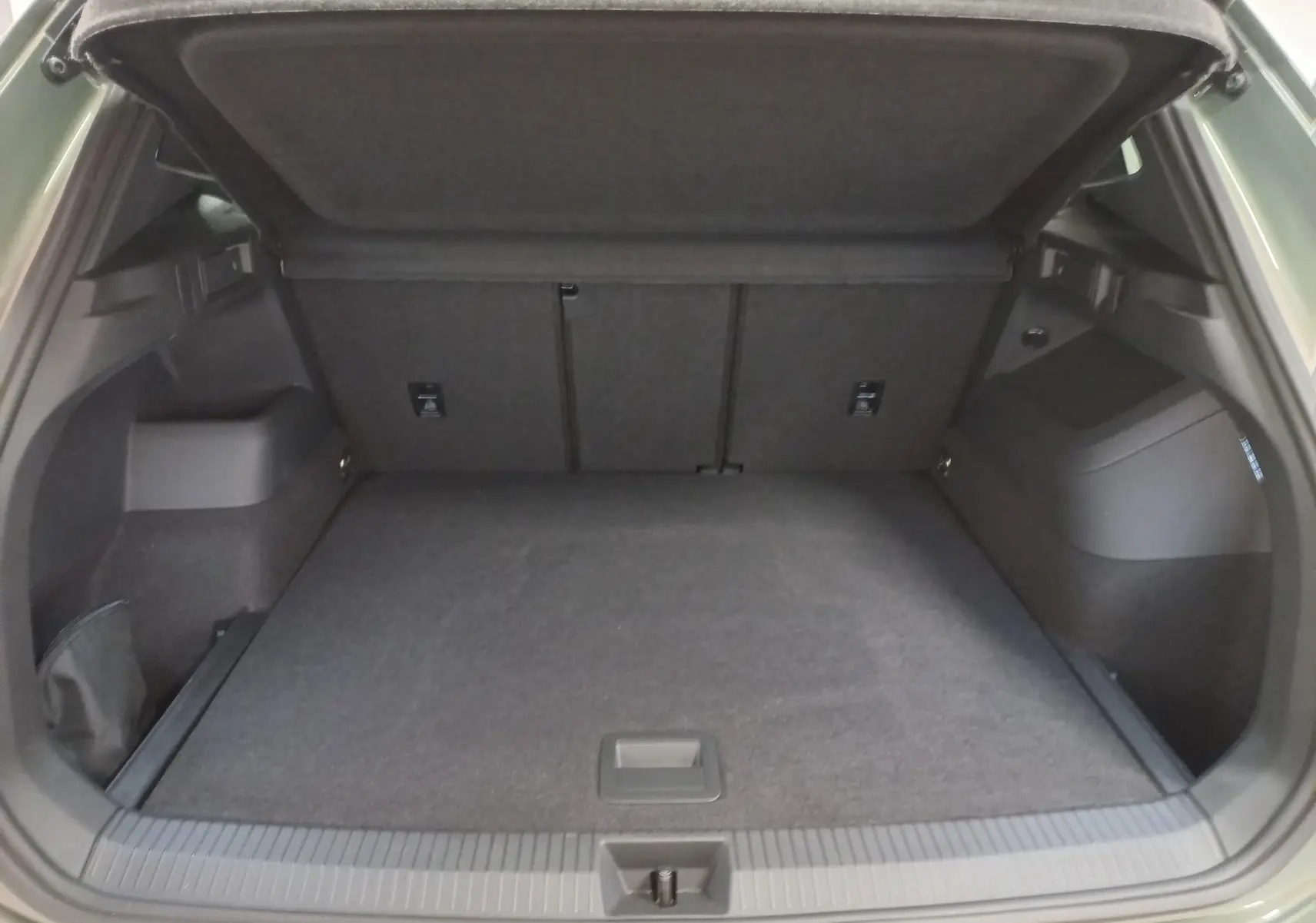 Coffre ouvert du Volkswagen Tiguan 2025 Vert Cipressino, vue arrière montrant l'espace de chargement vide et la plage arrière relevée.