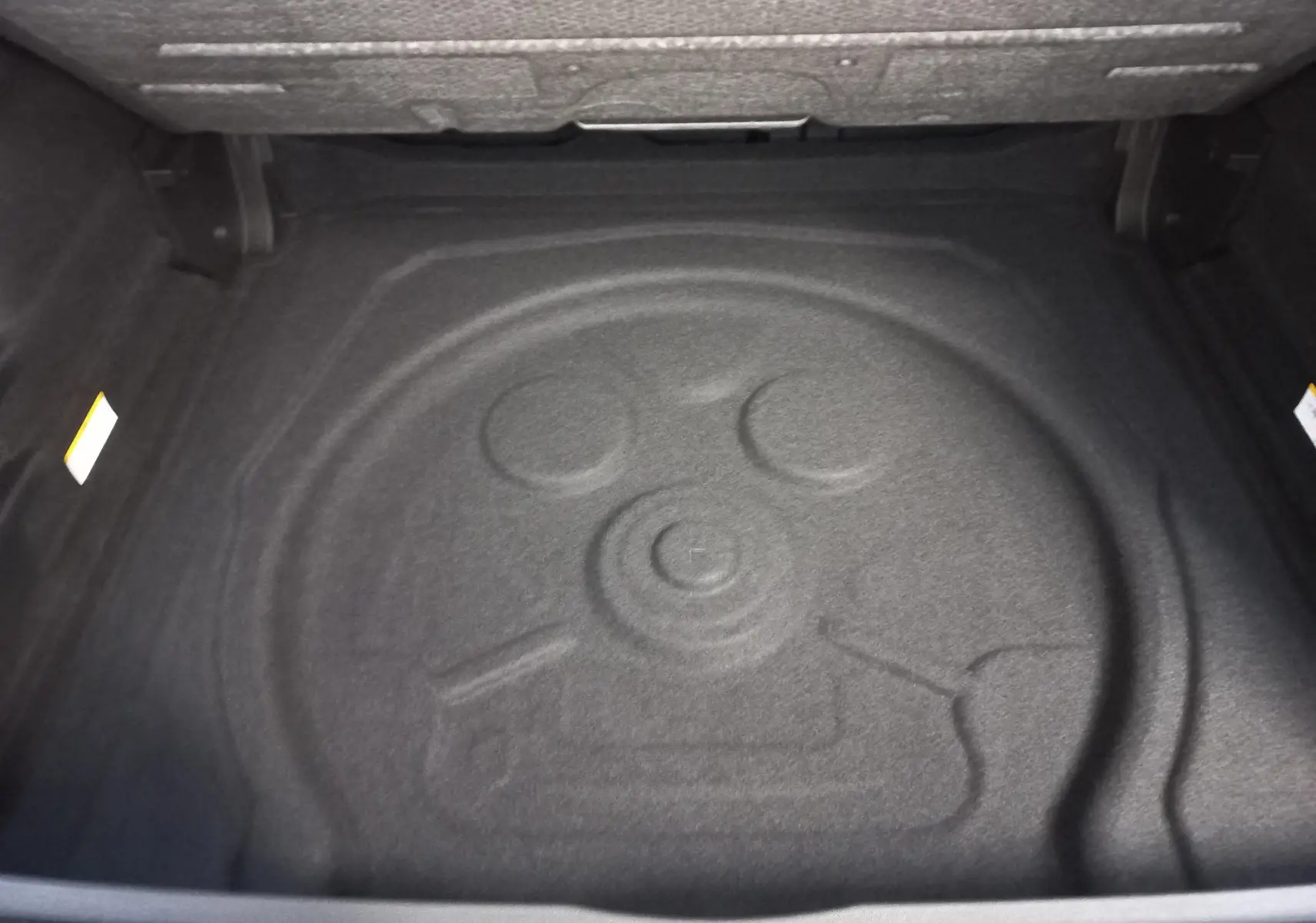 Coffre ouvert du Volkswagen Tiguan 2025, vue plongeante sur le rangement intérieur avec espace pour roue de secours.