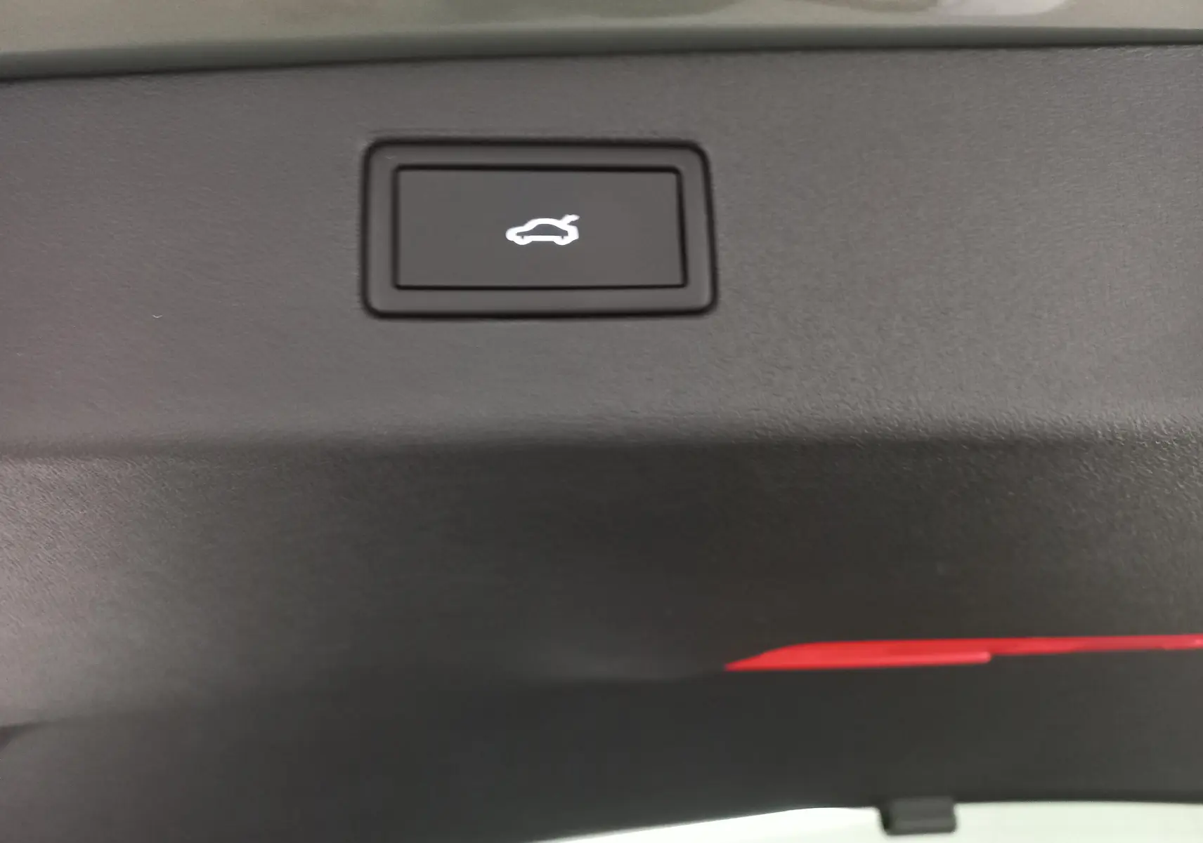 Bouton d'ouverture électrique du hayon sur le bord intérieur du coffre du Volkswagen Tiguan Vert Cipressino.