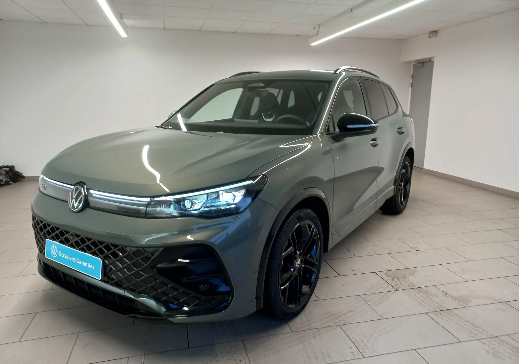 Volkswagen Tiguan 2025 vert Cipressino en 3/4 avant droit, avec calandre et jantes noires Black R-Line.