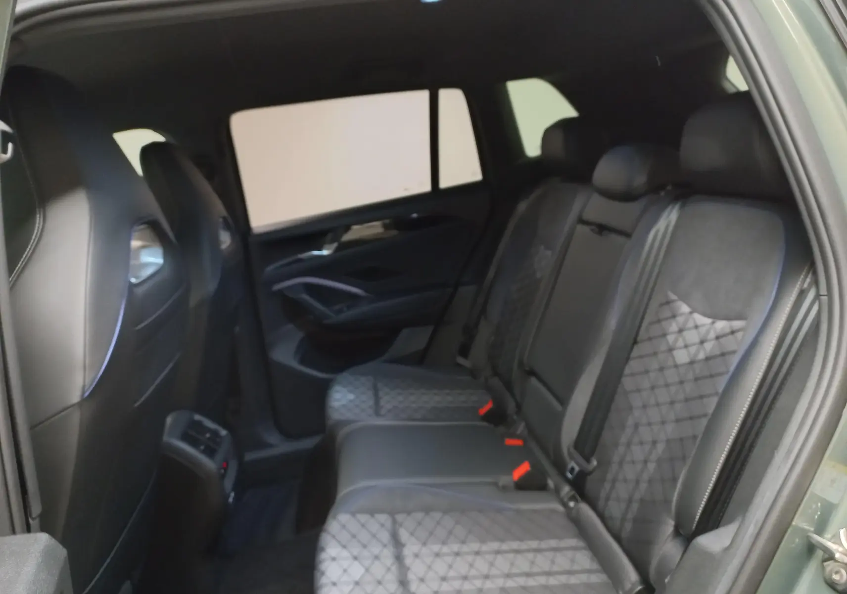 Vue intérieure arrière droite du Volkswagen Tiguan 2025, sièges en cuir noir avec surpiqûres et ceinture de sécurité visible.