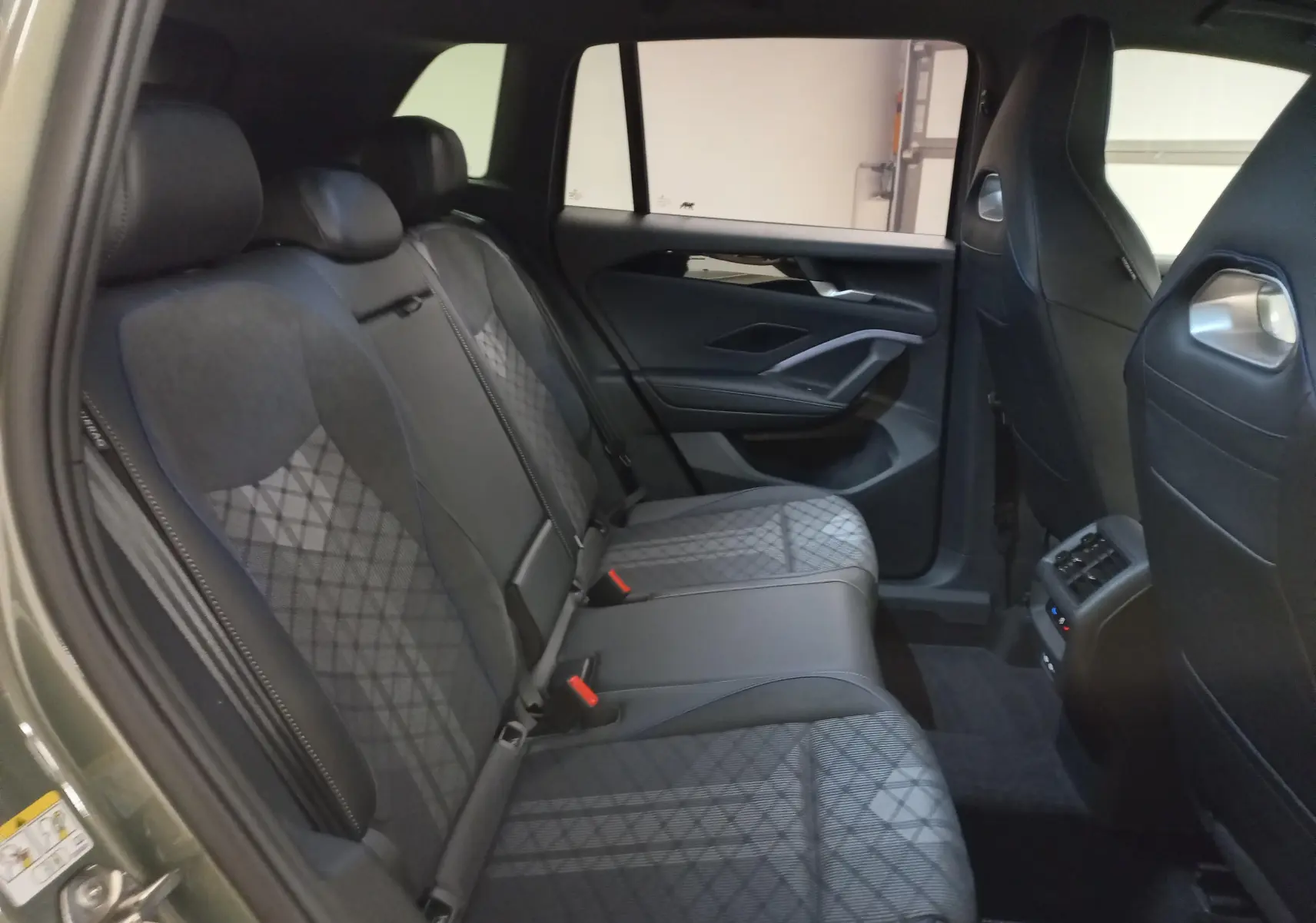 Vue intérieure des sièges arrière du Volkswagen Tiguan 2025, finition Black R-Line, avec sellerie en tissu et cuir noir.