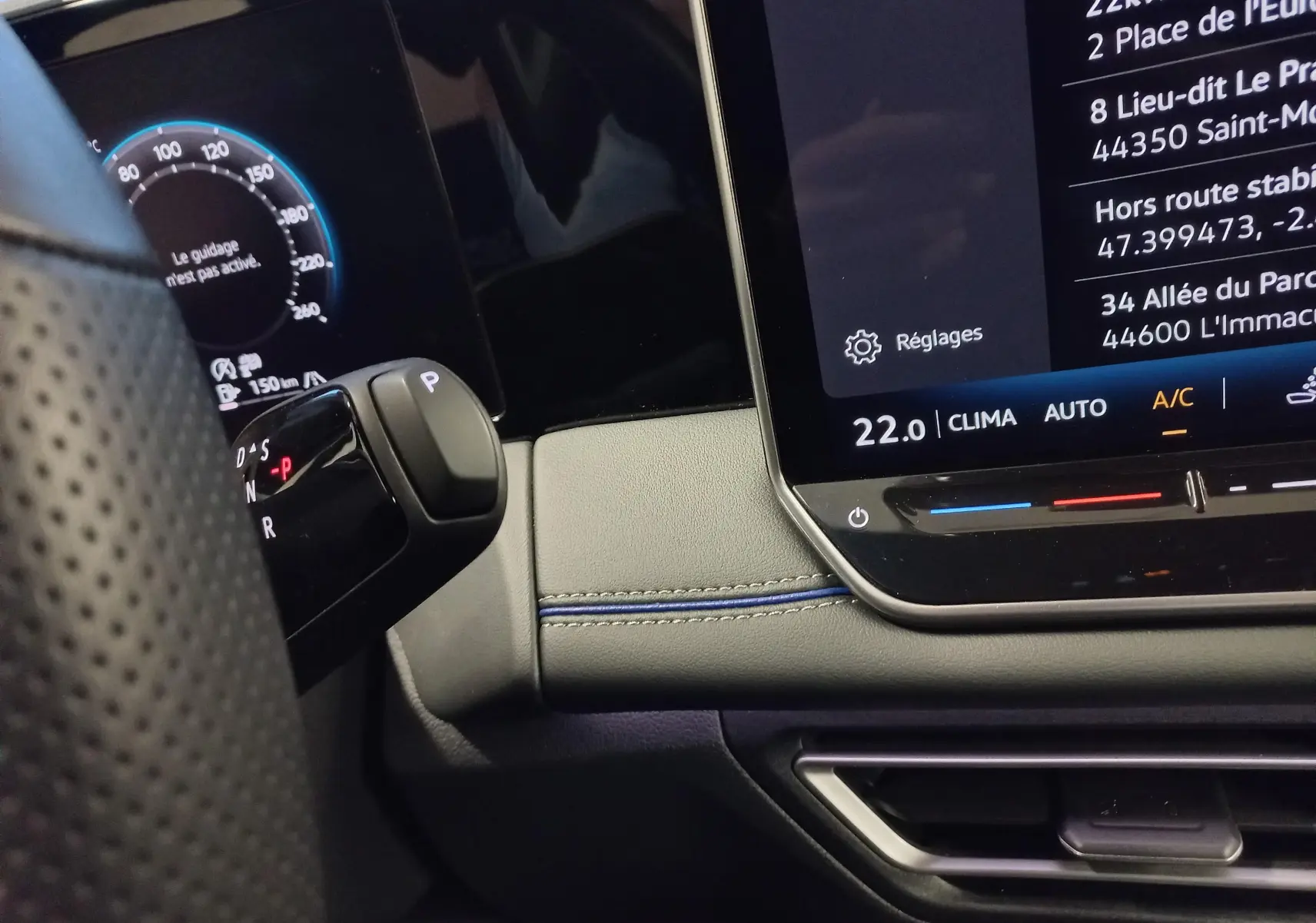 Gros plan sur la console centrale et levier de vitesses du Volkswagen Tiguan 1.5 eTSI 150ch DSG7, intérieur noir avec surpiqûres bleues.